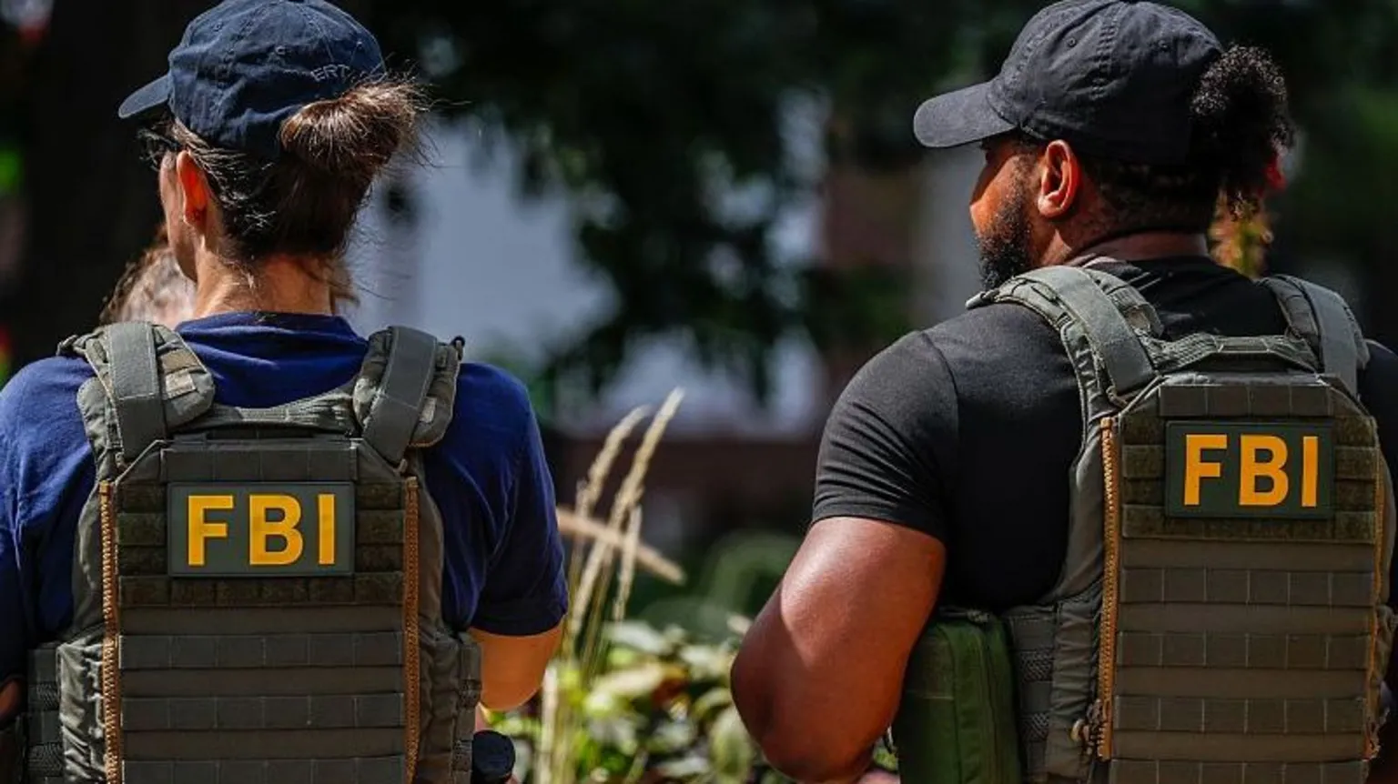 Two people wearing FBI-marked vests seen from behind; illustrative photograph